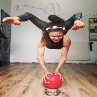 Girl puts shades on whilst balancing with her hands on a ball using just her feet